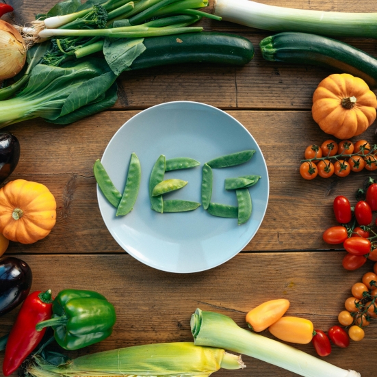 tallerken med ordet VEG og grøntsager omkring
