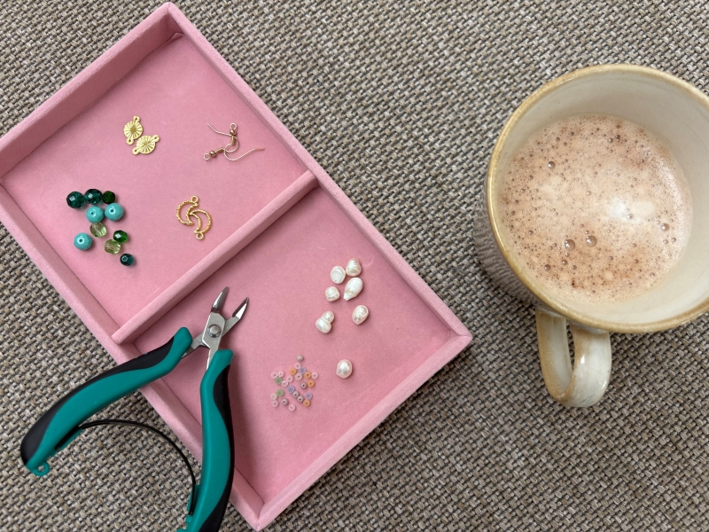 Lyserød bakke med perler og en kop varm kakao