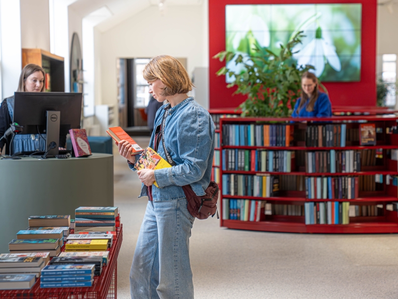 Kvinde der læser på bagsiden af en bog på Silkeborg Bibliotek