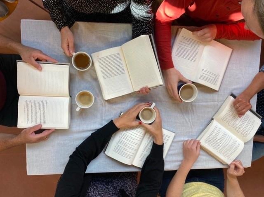 Et billede af 4 personer omkring et bord og 4 opslåede bøger